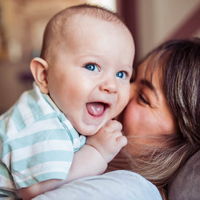 Frau kuschelt mit lachendem Baby